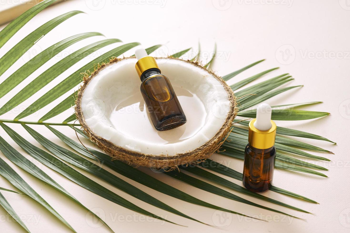 aceite de coco en botella con nueces abiertas y pulpa en frasco, fondo de hoja de palma verde. productos cosméticos naturales. foto