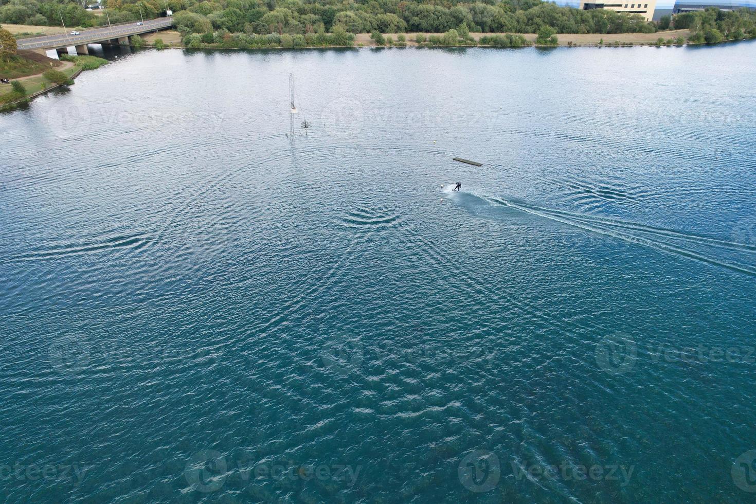 Beautiful Aerial Drone's Camera  Footage of Willen Lake and Park which is located at Milton Keynes, England. People are Enjoying at Lake on a Hot Sunny Day of Summer photo