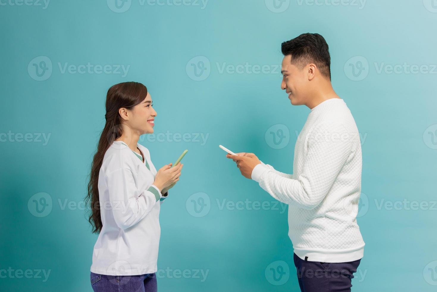 amazing couple whose use smart phone read news look with interest isolated light blue background photo