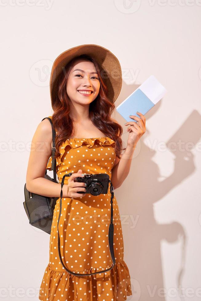 Expressive tourist woman in summer casual clothes, hat holding passport, tickets isolated on beige background. Female traveling abroad to travel weekends getaway. Air flight journey concept photo