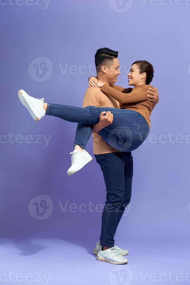 Full length photo of handsome man holding beautiful woman in his arms