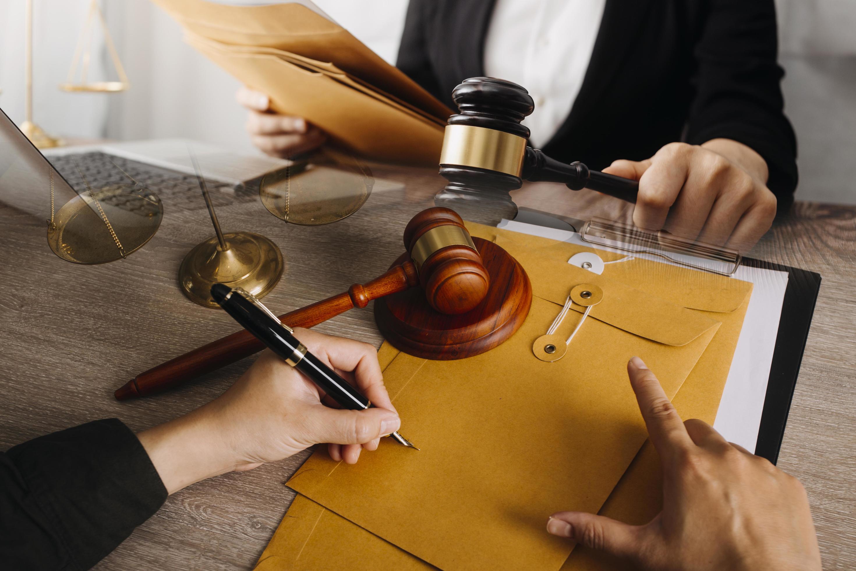 abogado masculino que trabaja con papeles de contrato y mazo de madera en tabel en la sala del