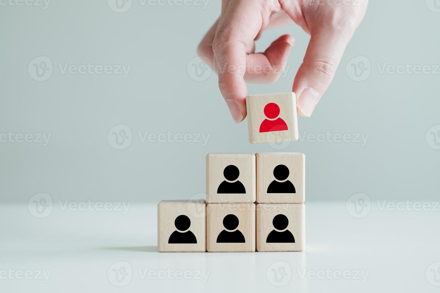 Hand hold red people icon on block. Human resources management and recruitment business hiring concept, corporate hierarchy, recruiter complete team by one leader person, finding professional staff. photo