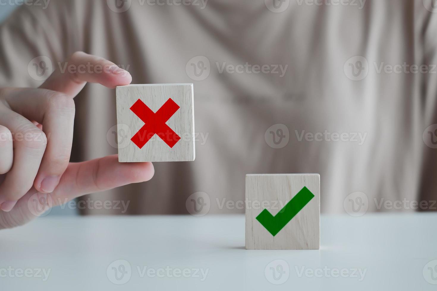 Woman hand pick wrong or cross icon on wood cube and check mark symbol stand on table for true or false changing mindset or way of adapting to change leader and transform quiz answer and poll concept. photo