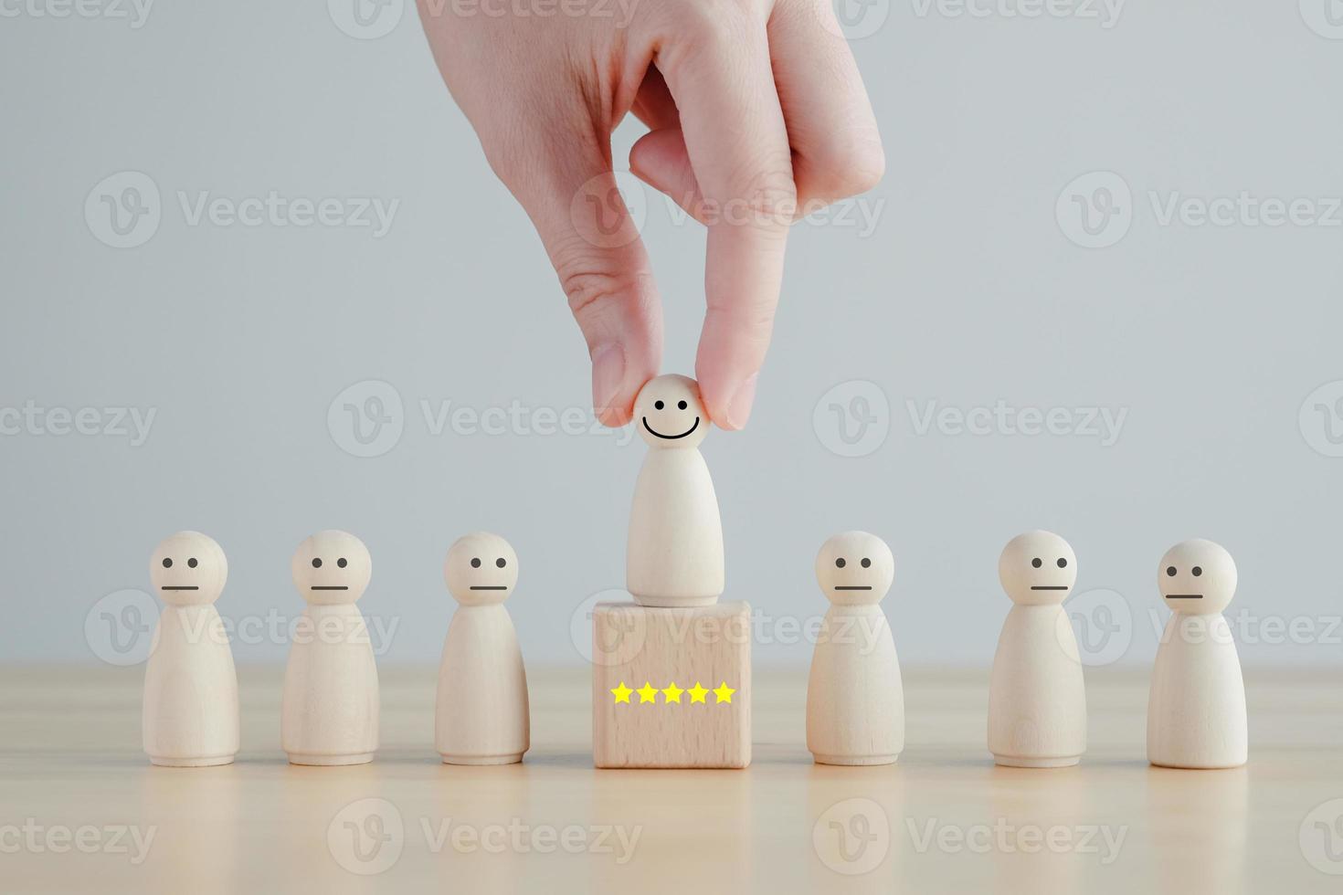 Hand pick happy face wooden figure. Customer service rating experience and feedback emotion and satisfaction survey. Human Resources management choosing positive attitude to team. photo