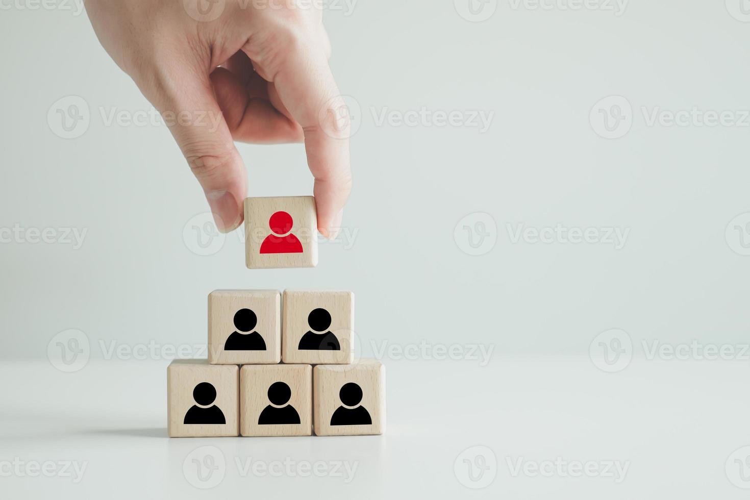 Hand hold red people icon on block. Human resources management and recruitment business hiring concept, corporate hierarchy, recruiter complete team by one leader person, finding professional staff. photo