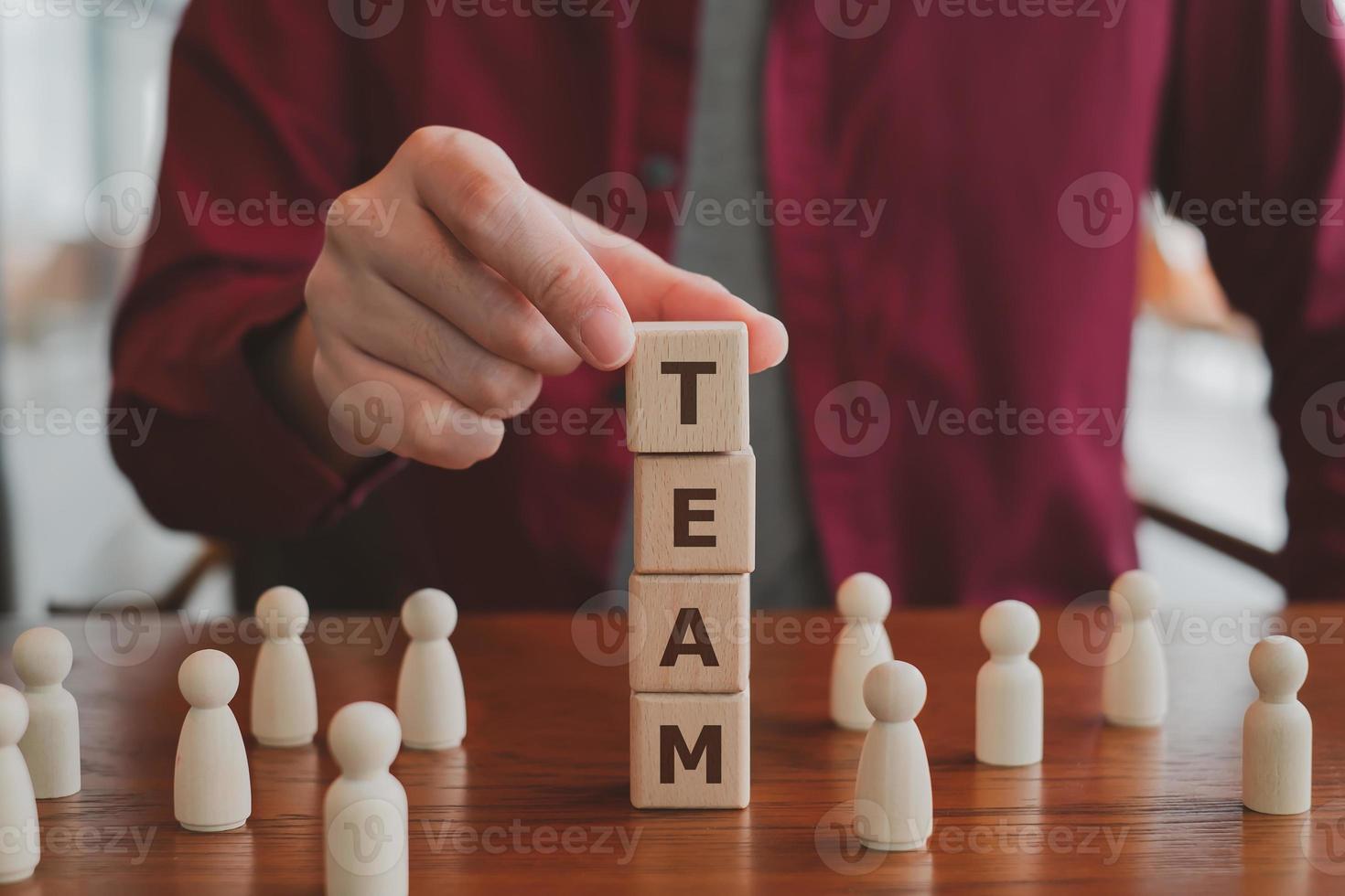 Businessman holding wood blocks TEAM word and different wooden figure person. concept for teamwork, leadership and team leader. photo