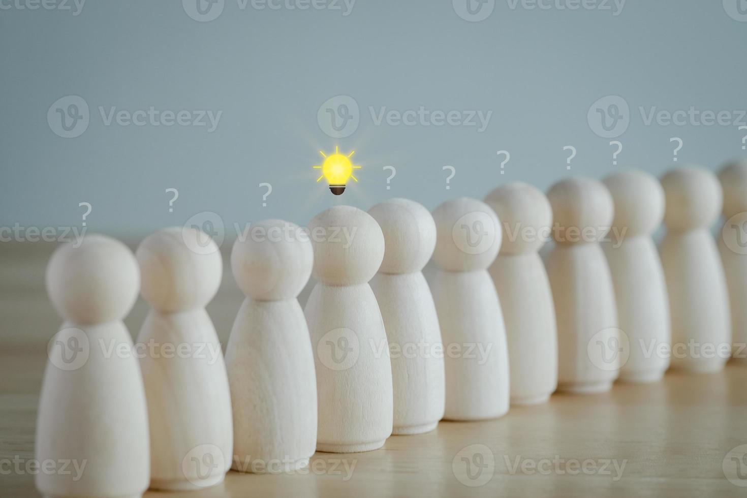 Leader with idea and innovation and creativity concept. Creative process concept and problem solution. Wooden human with  glowing light bulb among many question mark. Standing out from the crowd. photo
