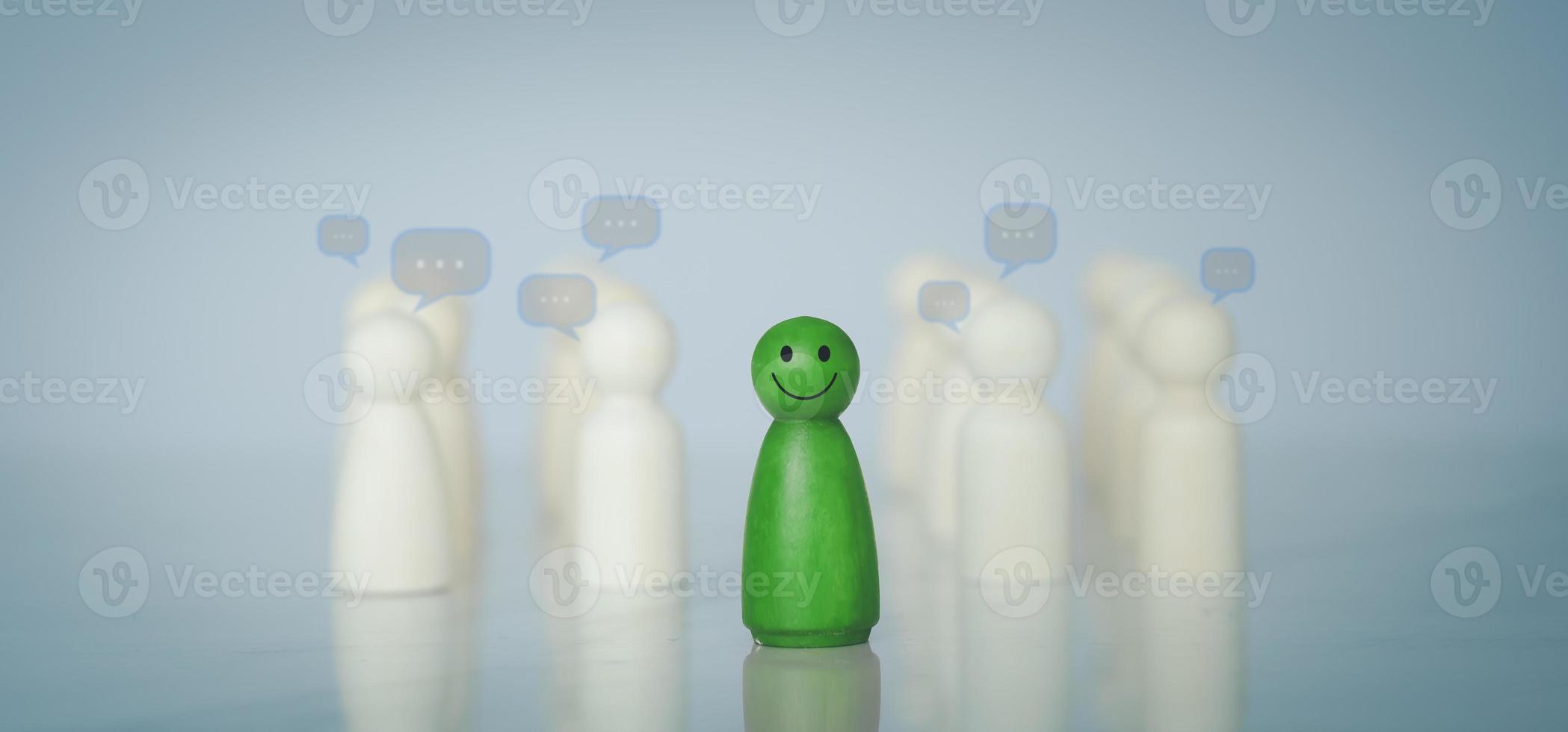 Green wood figure with happy face standing out from the crowd of different people. Individuality, Introvert, Not care when someone is talking, Unique human shape, Leadership,  Human resource. photo
