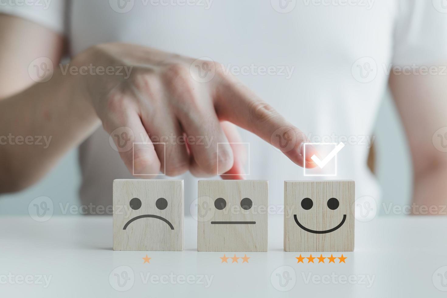 Customer service rating experience and feedback emotion and satisfaction survey with star and negative, neutral and positive facial expressions. hand choose 5 star happy smiley face icon on wood cube. photo