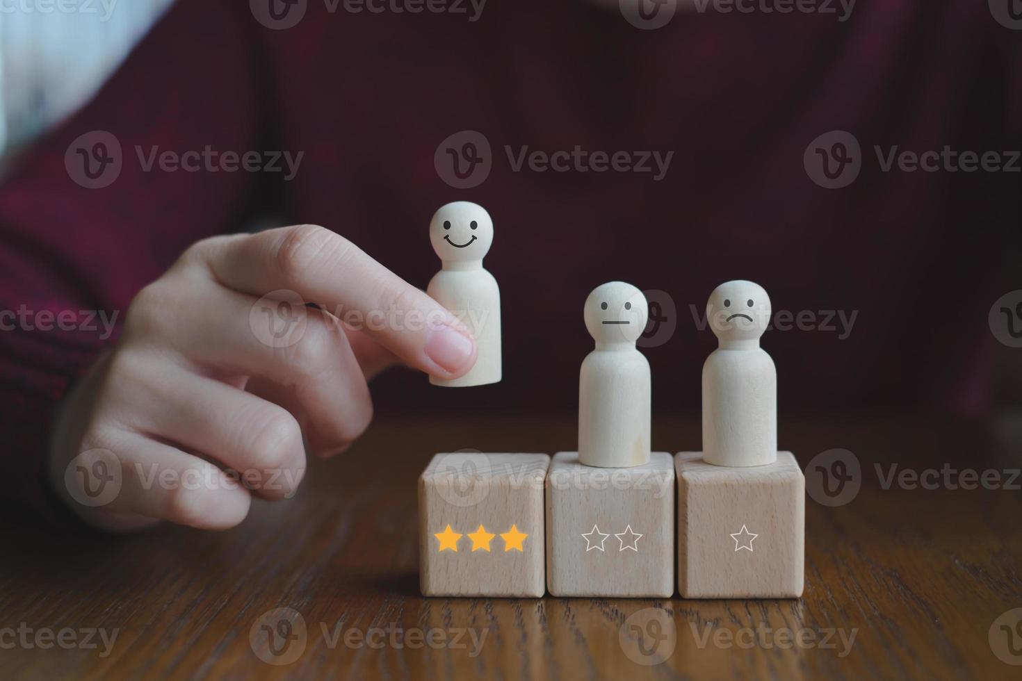 Hand pick happy face wooden figure. Customer service rating experience and feedback emotion and satisfaction survey. Human Resources management choosing positive attitude to team. photo