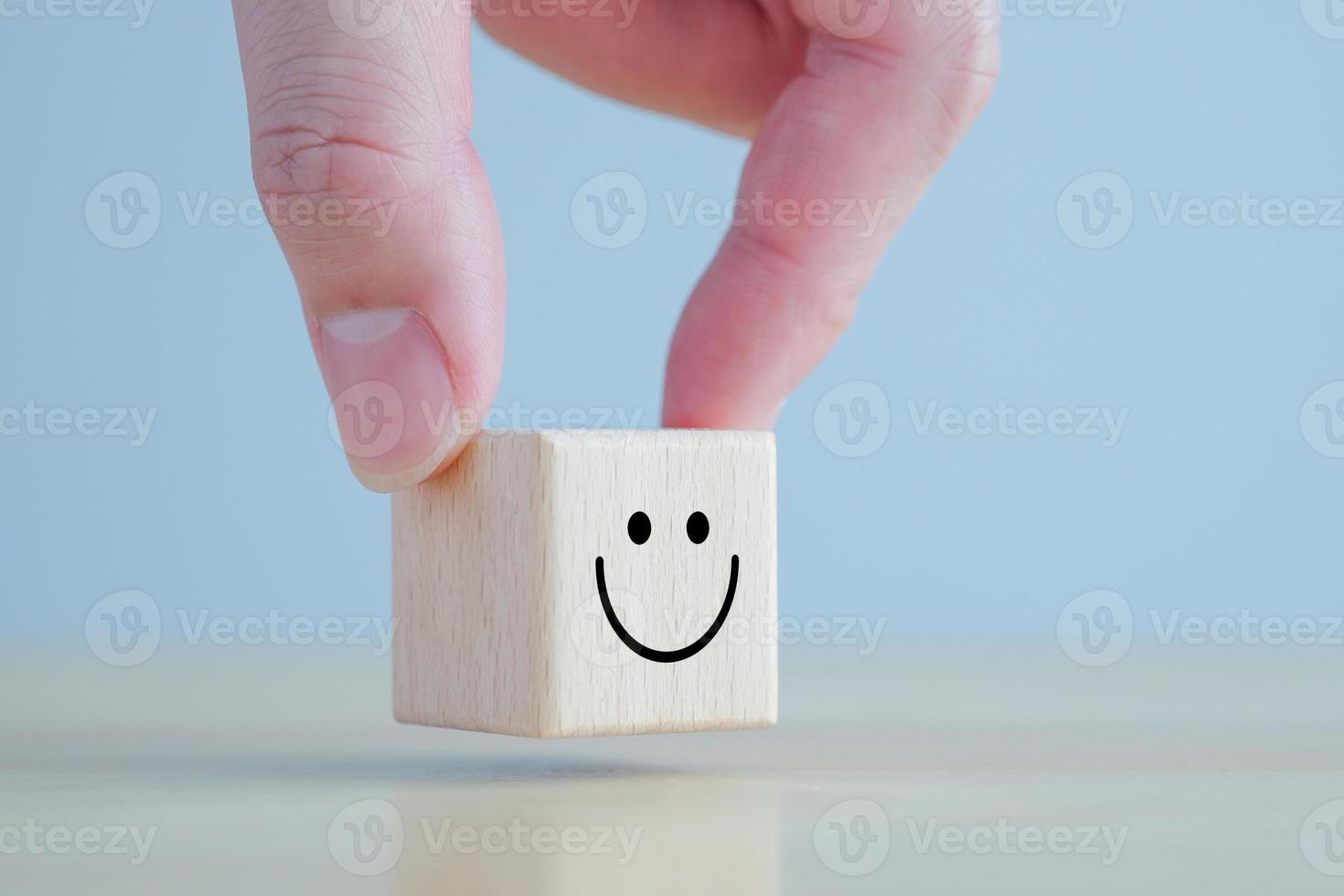 Emotion, Mental, Customer service evaluation and satisfaction survey concept. Review, Feedback. Hand holding happy face on wooden blocks. photo