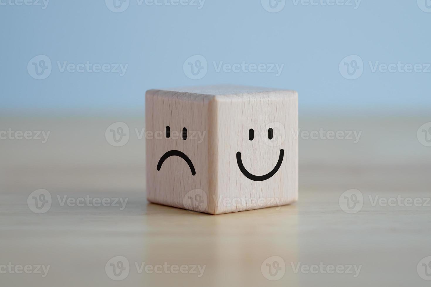 cara feliz y cara triste en cubo de bloque de madera para selección de mentalidad positiva, calificación de servicio, concepto de satisfacción. foto