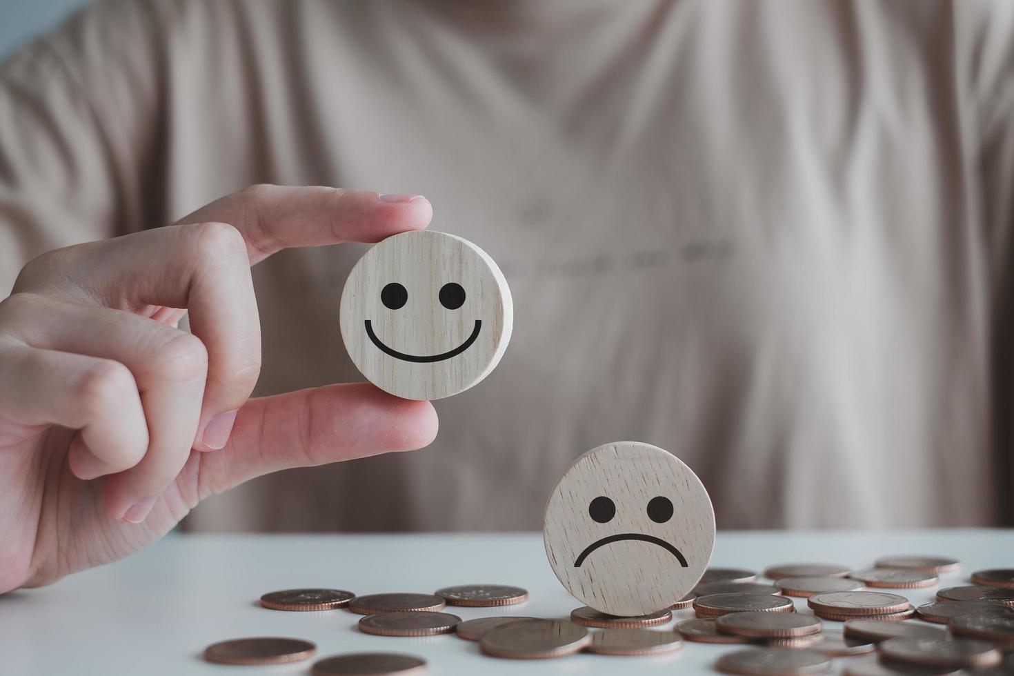 Business service rating experience, satisfaction survey concept. Customer hand picked happy smiley face and blurred sad face icon on wood circle. photo