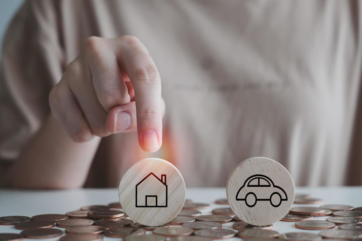 Makes a choice for investment, save money business and finacial or insurance concept. Buyer decides what to buy. Woman hand choose house that is options between car and home with many coins on floor. photo