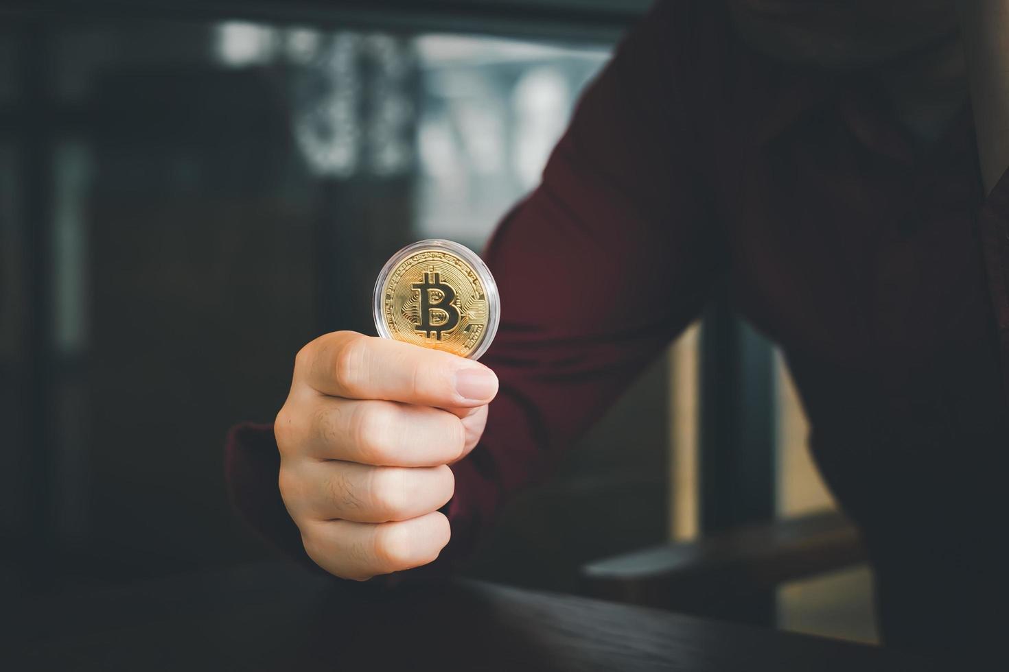 Bitcoin gold coin. Hand holding a gold coin bitcoin, cryptocurrency, btc crypto currency. photo