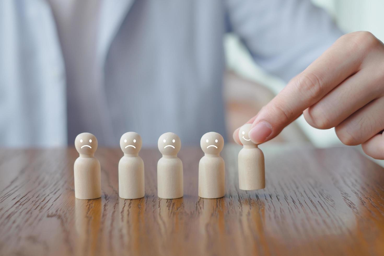 Hand pick happy face wooden figure. Customer service rating experience and feedback emotion and satisfaction survey. Human Resources management choosing positive attitude to team. photo