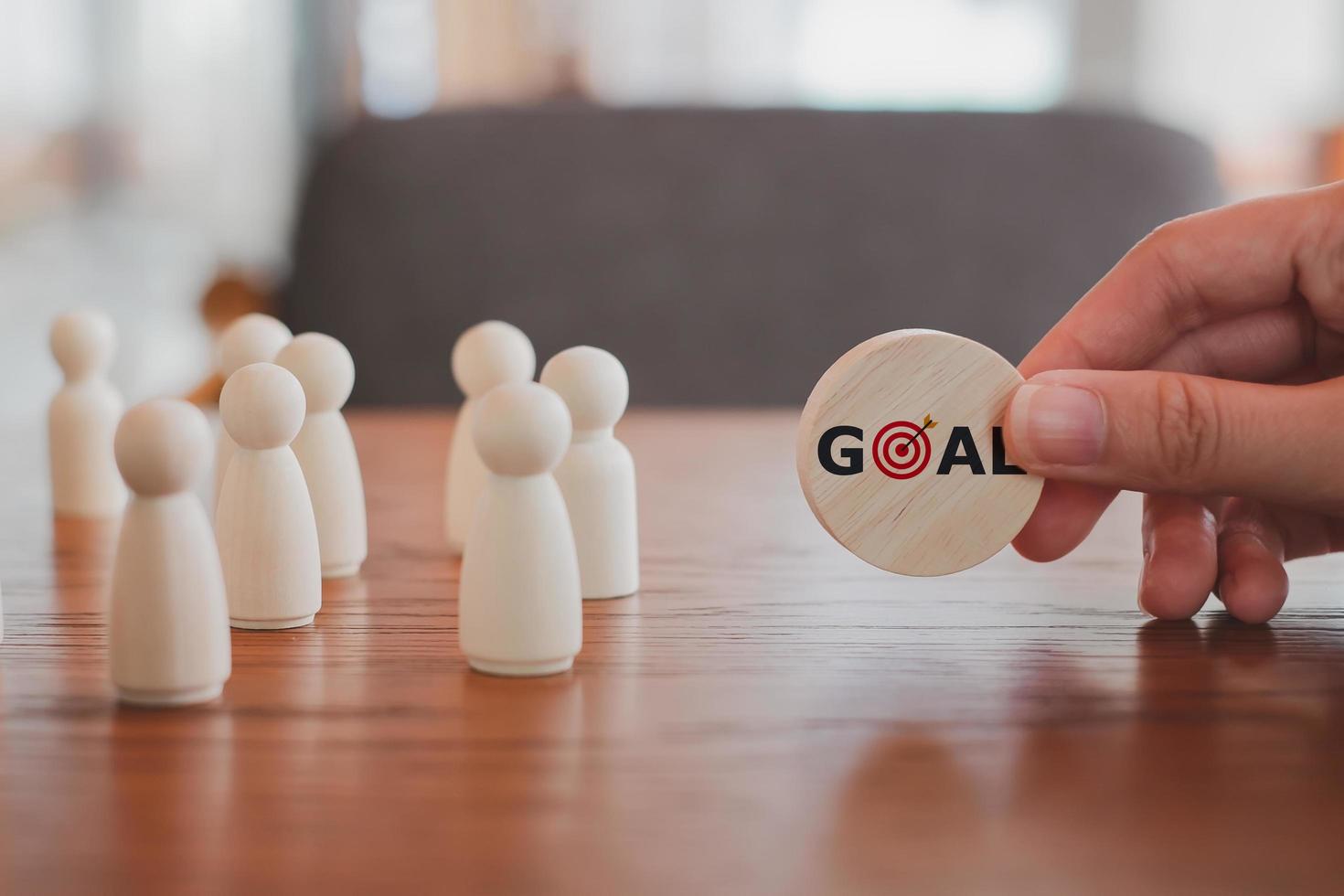 Hand holding wood blocks GOAL word with dart board symbols and different wooden figure person. Business strategy, Action plan, Goal and target. Team Management, Teamwork, leadership. photo