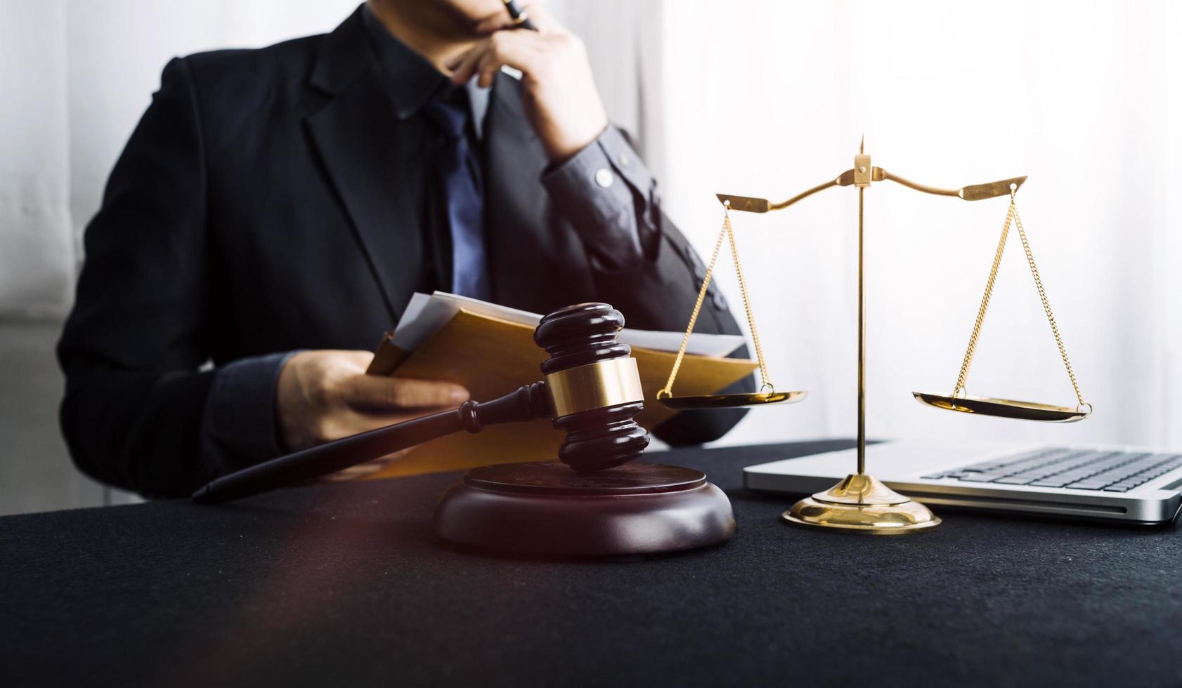 Justice and law concept.Male judge in a courtroom with the gavel, working with, computer and docking keyboard, eyeglasses, on table in morning light photo