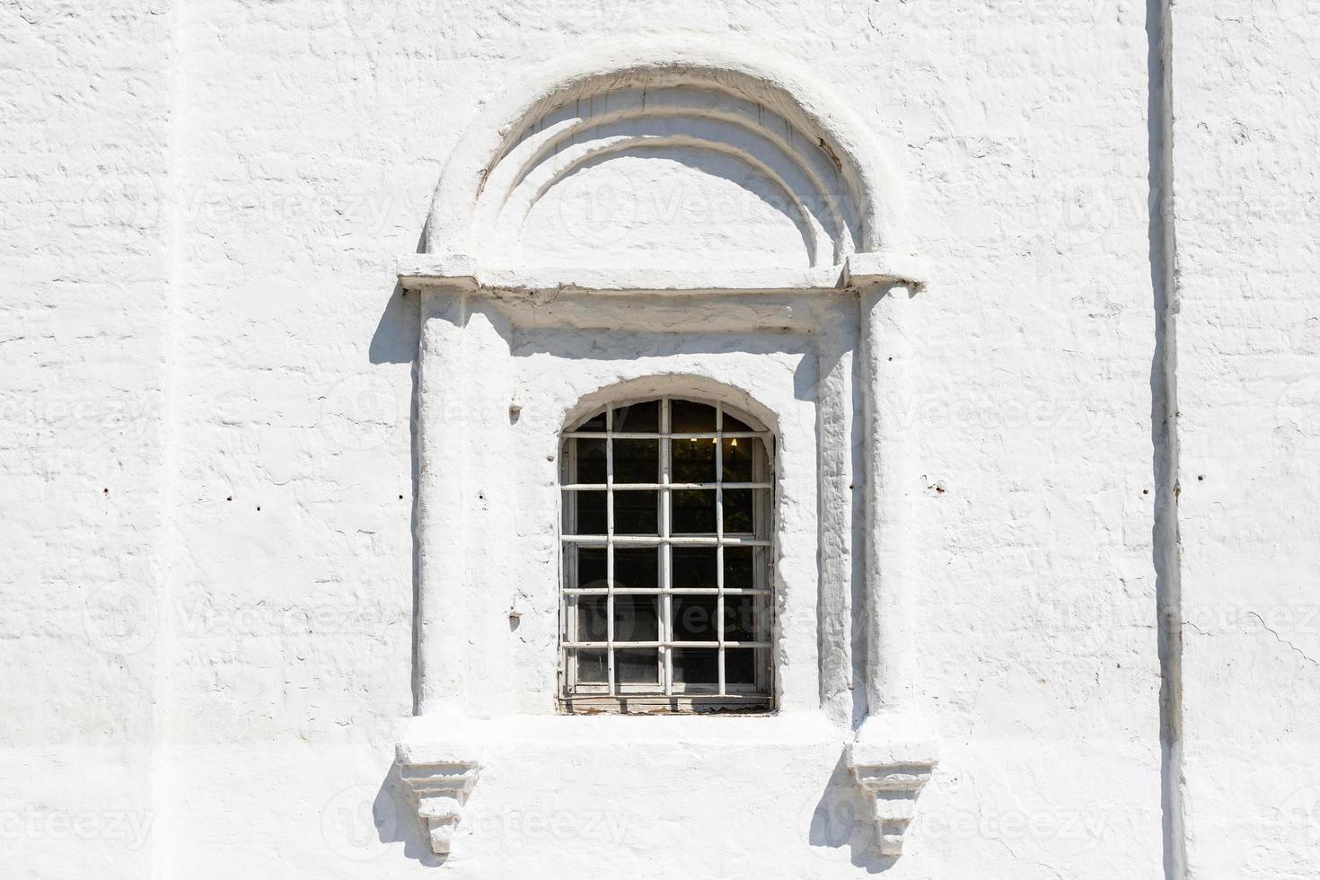 grille window in wall of ancient russian church photo