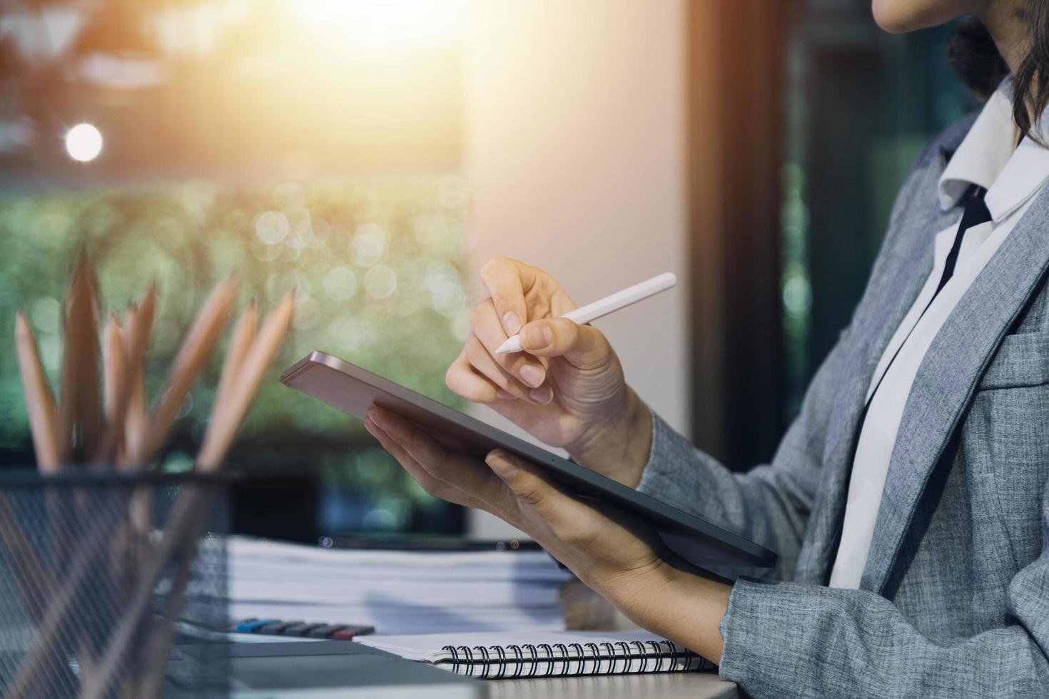 Woman accountant use calculator and computer with holding pen on photo