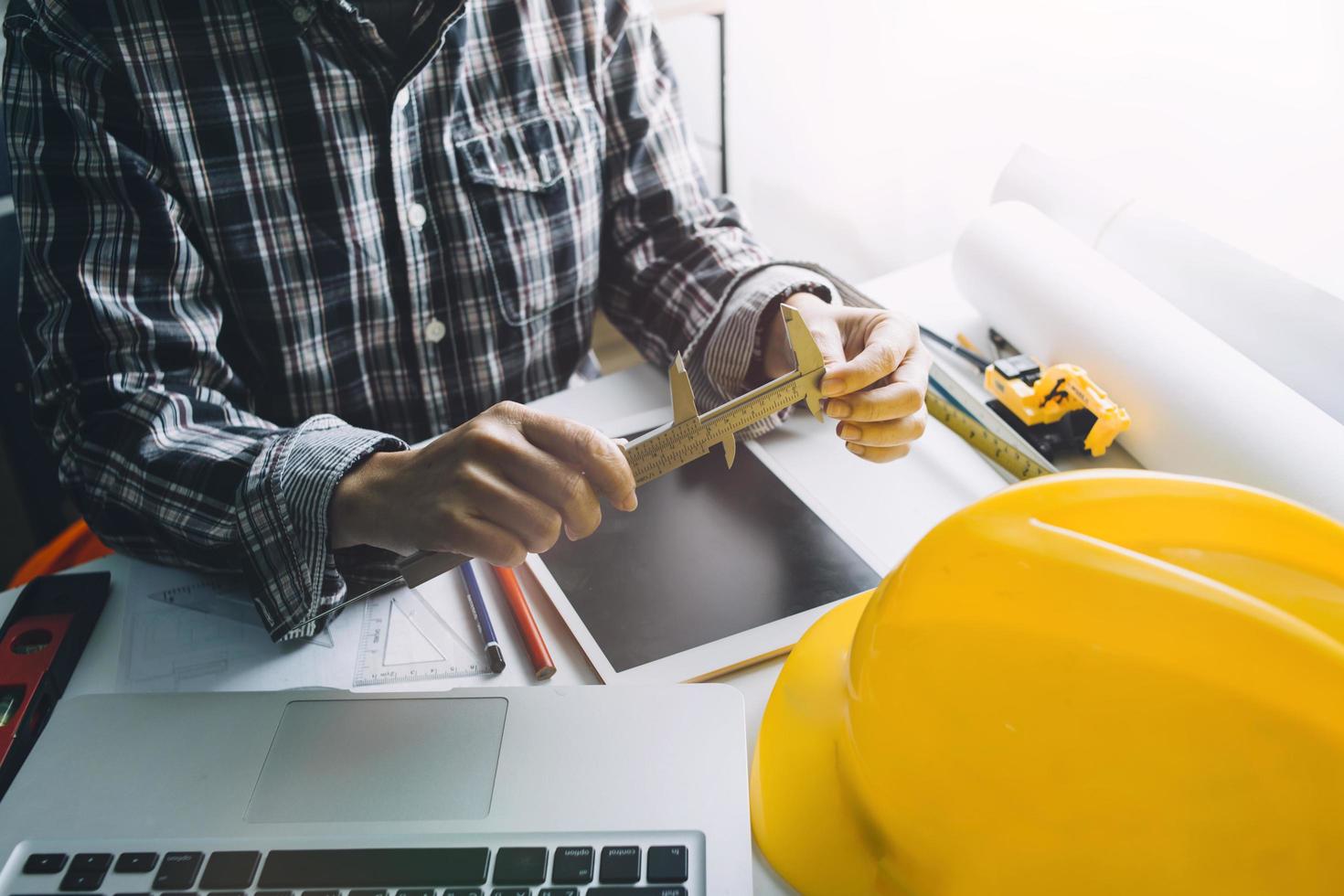 Two colleagues discussing data working and tablet, laptop with on on architectural project at construction site at desk in office photo