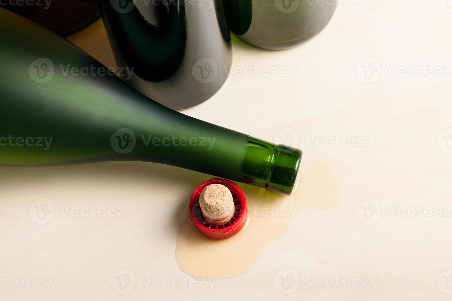 bottle in spilled cognac near empty wine bottles photo