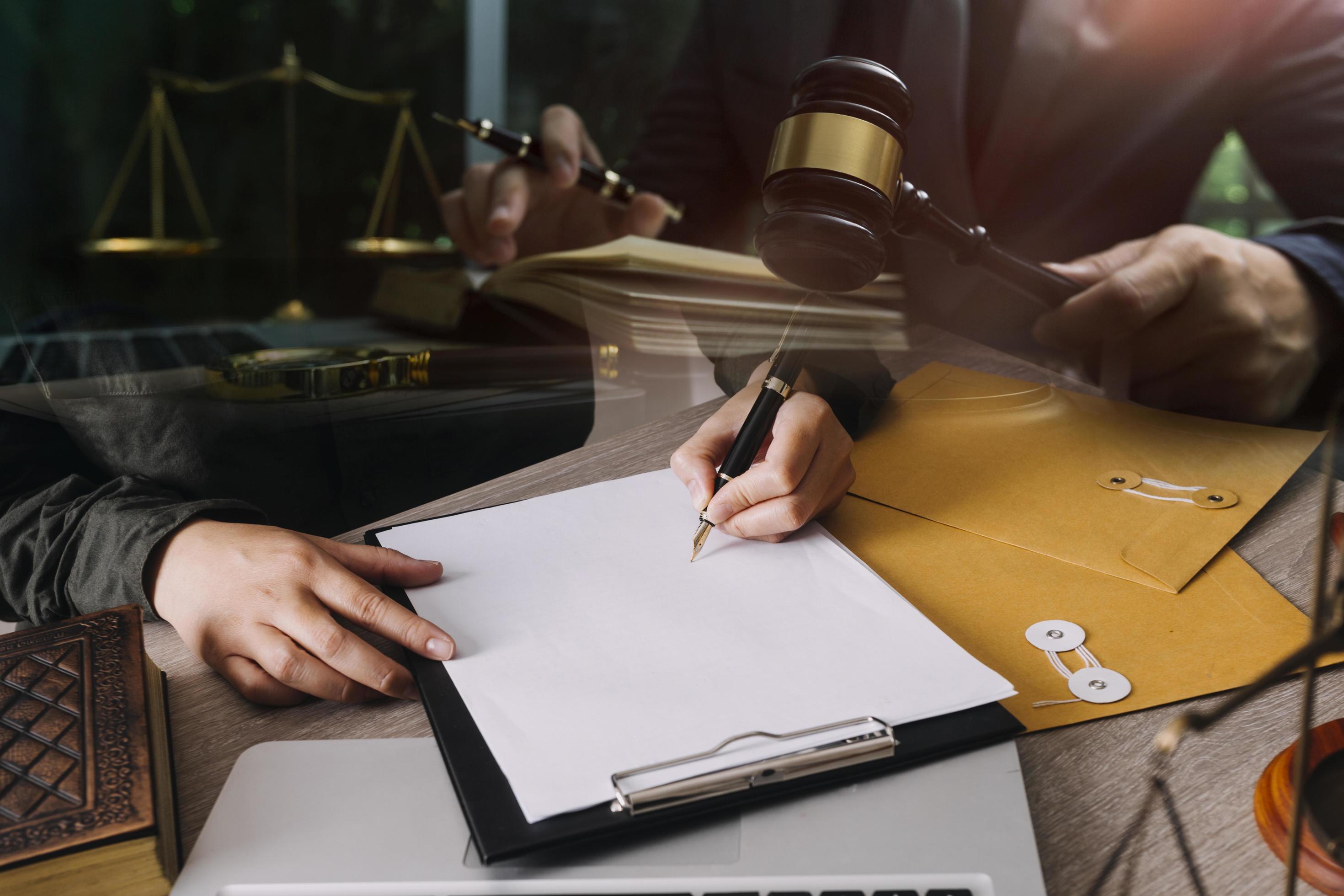 abogado masculino que trabaja con papeles de contrato y mazo de madera en tabel en la sala del