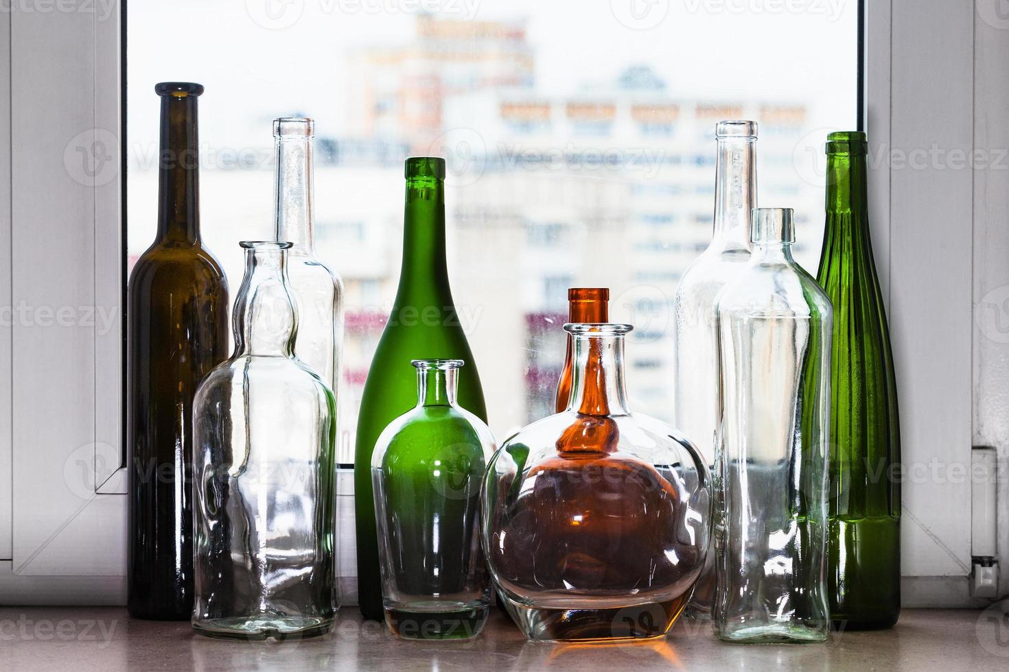 different empty bottles on sill and view of city photo