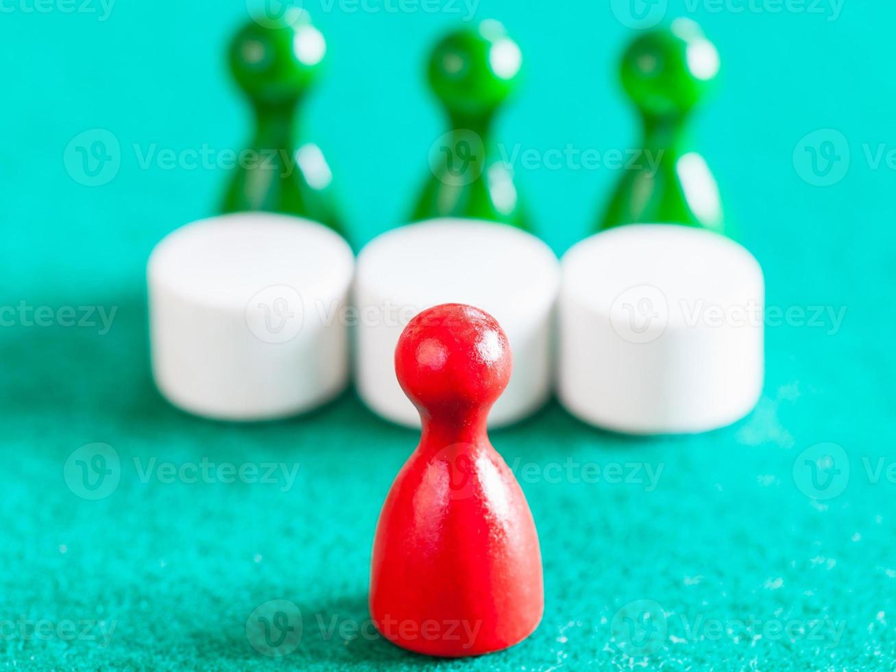 red pawn in front of three green pawns with tables photo