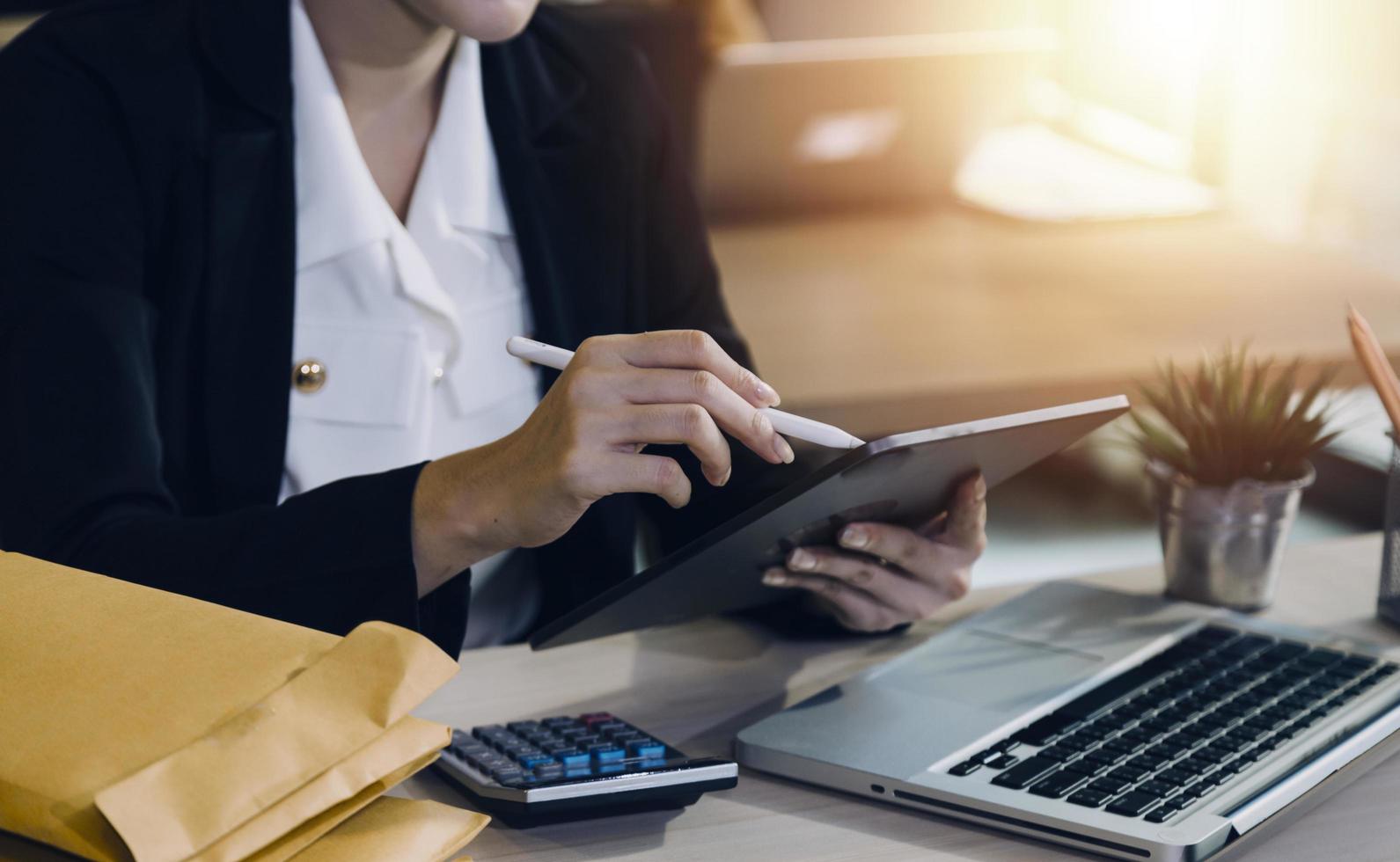 Woman accountant use calculator and computer with holding pen on photo