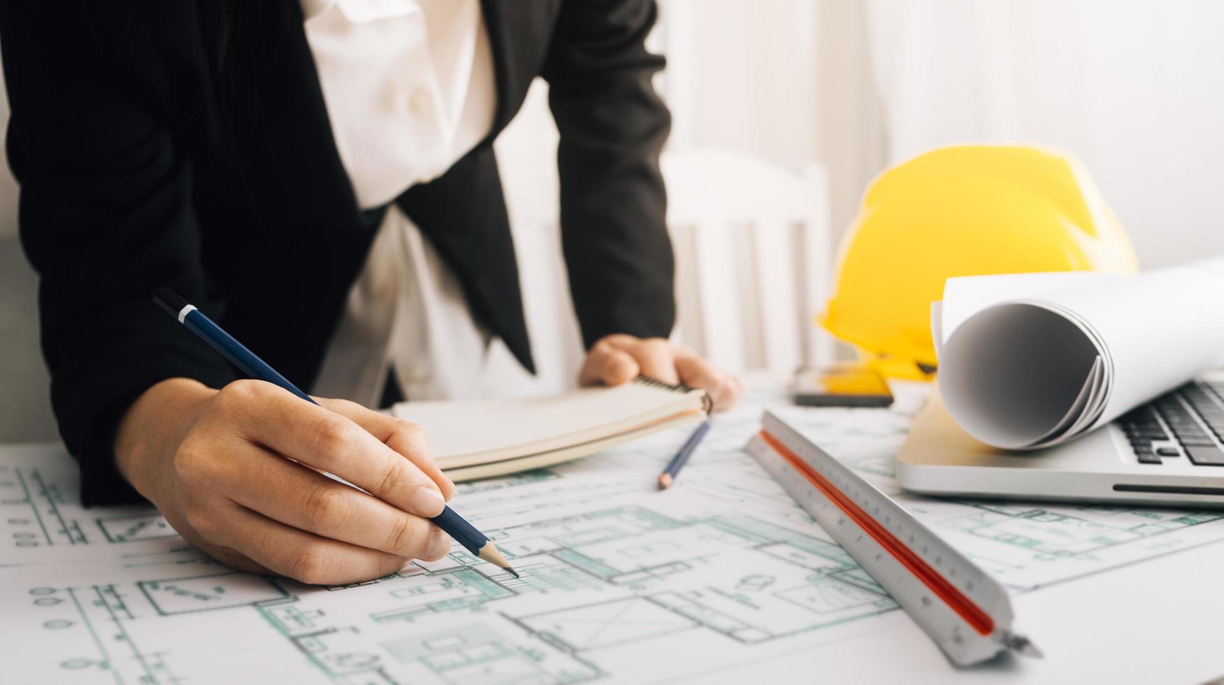 Two colleagues discussing data working and tablet, laptop with on on architectural project at construction site at desk in office photo