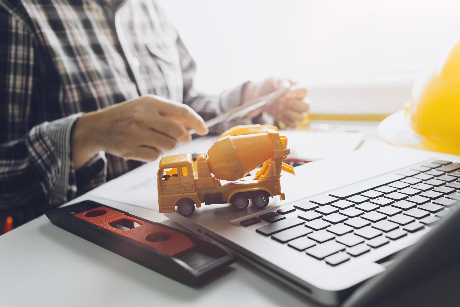 Two colleagues discussing data working and tablet, laptop with on on architectural project at construction site at desk in office photo