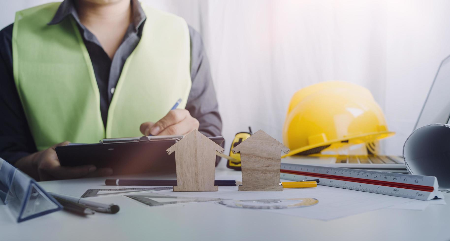 Two colleagues discussing data working and tablet, laptop with on on architectural project at construction site at desk in office photo