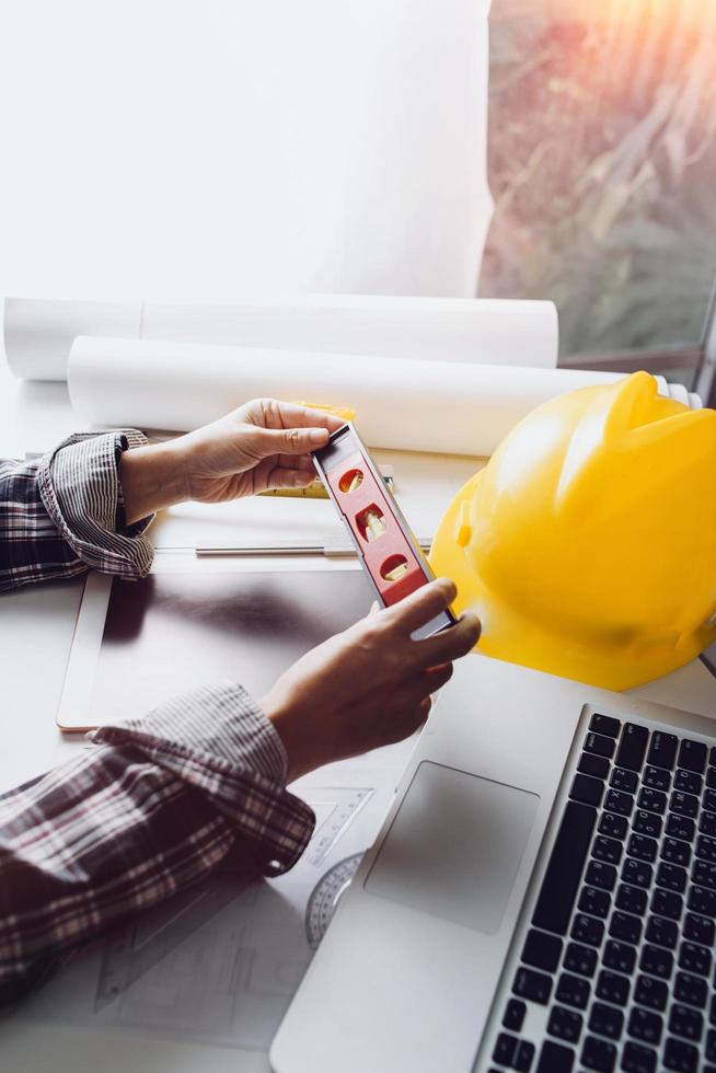 Two colleagues discussing data working and tablet, laptop with on on architectural project at construction site at desk in office photo