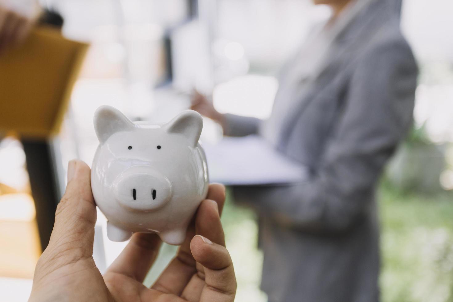 businessman hand putting coin in piggy bank. Saving money concept, business finance and investment. photo