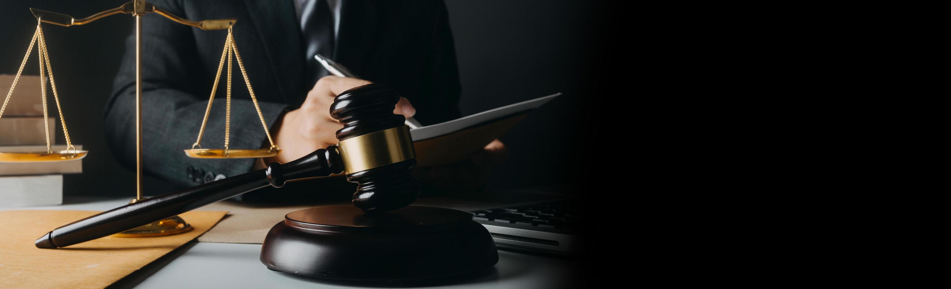 Justice and law concept.Male judge in a courtroom with the gavel, working with, computer and docking keyboard, eyeglasses, on table in morning light photo