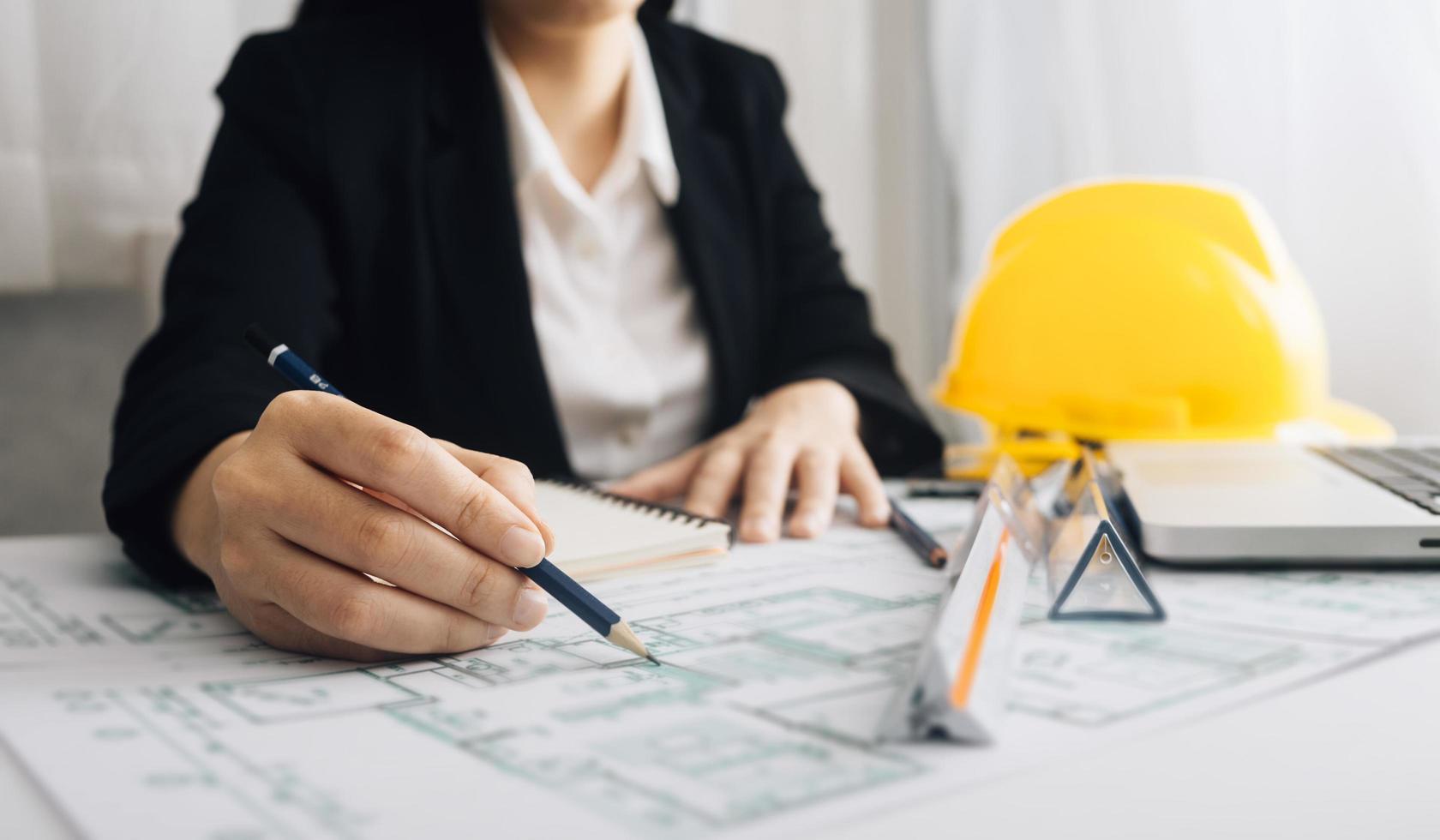 Two colleagues discussing data working and tablet, laptop with on on architectural project at construction site at desk in office photo