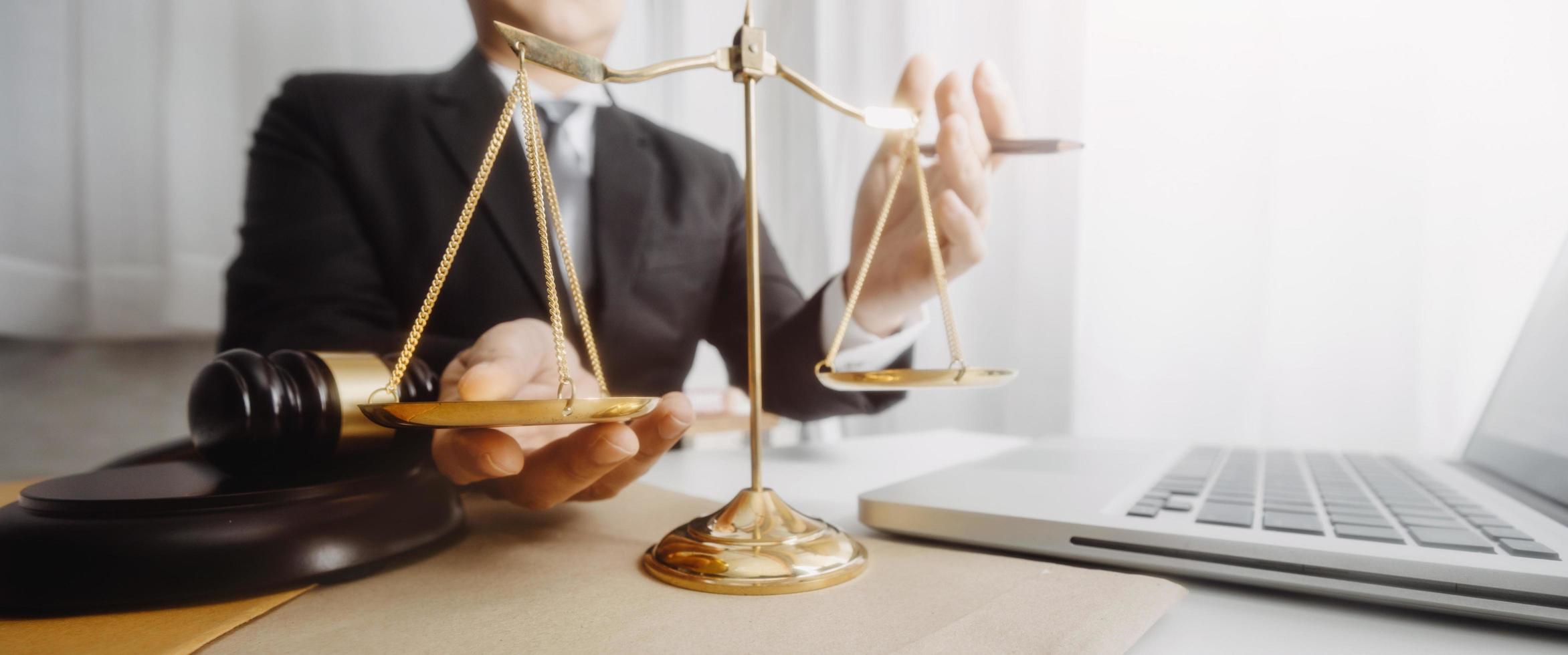 Justice and law concept.Male judge in a courtroom with the gavel, working with, computer and docking keyboard, eyeglasses, on table in morning light photo