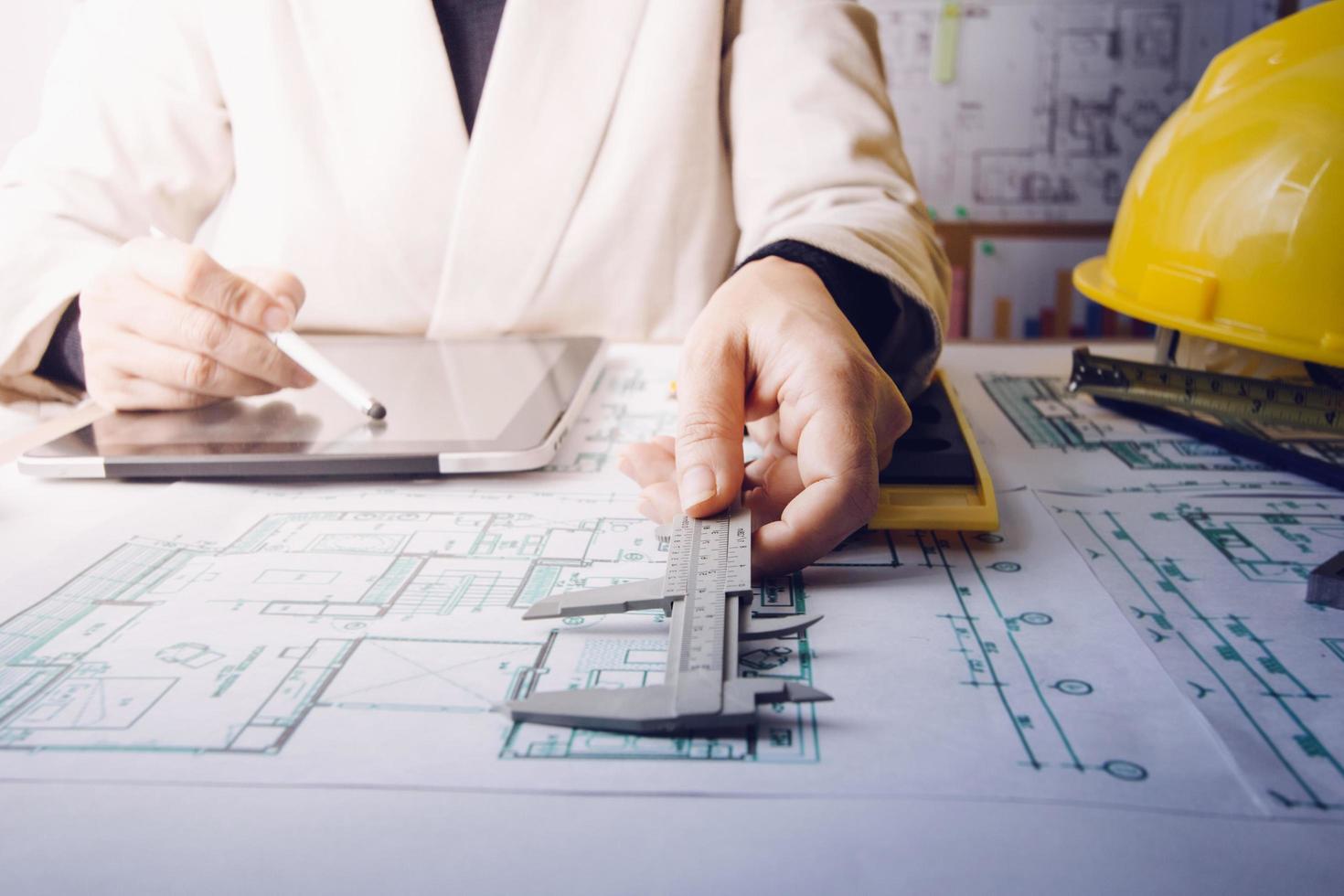 Two colleagues discussing data working and tablet, laptop with on on architectural project at construction site at desk in office photo