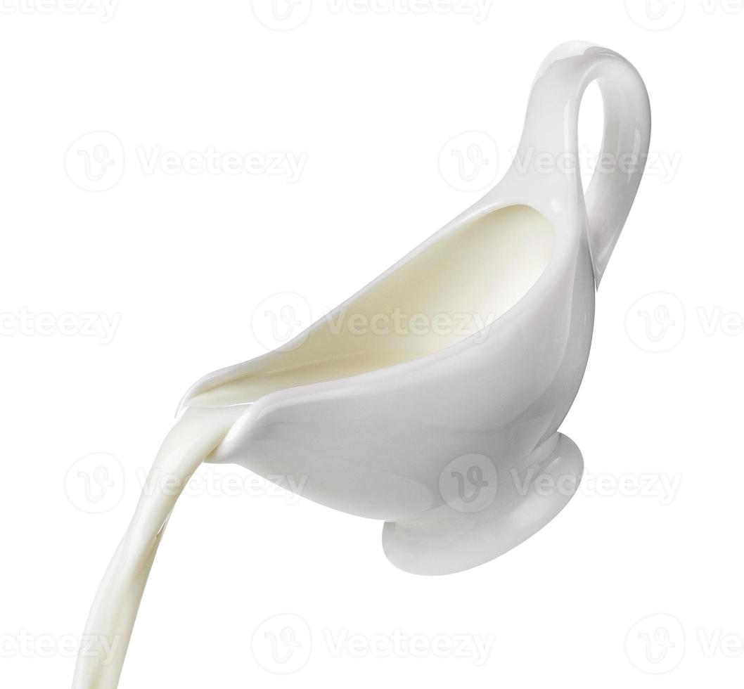 Pouring cream from creamer isolated on white background, flowing milk photo