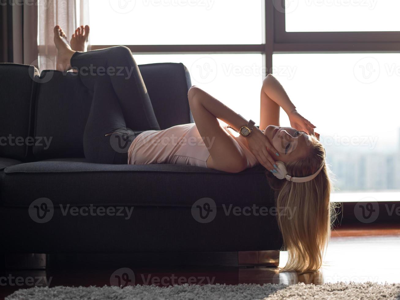 Lovely Blond Woman Listening To Music while resting on couch photo