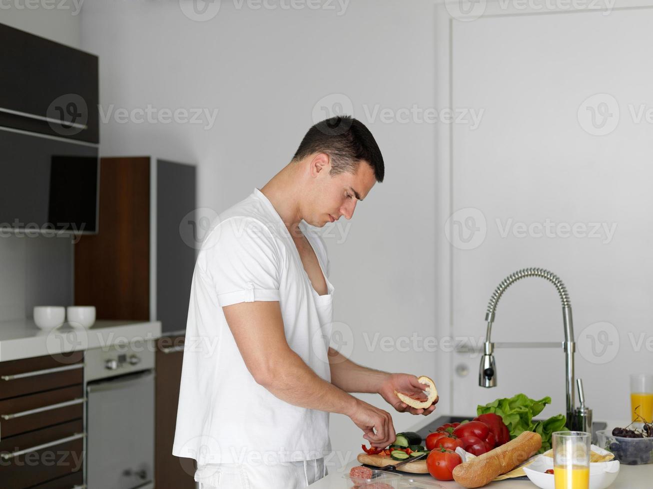 man cooking at home preparing salad in kitchen photo