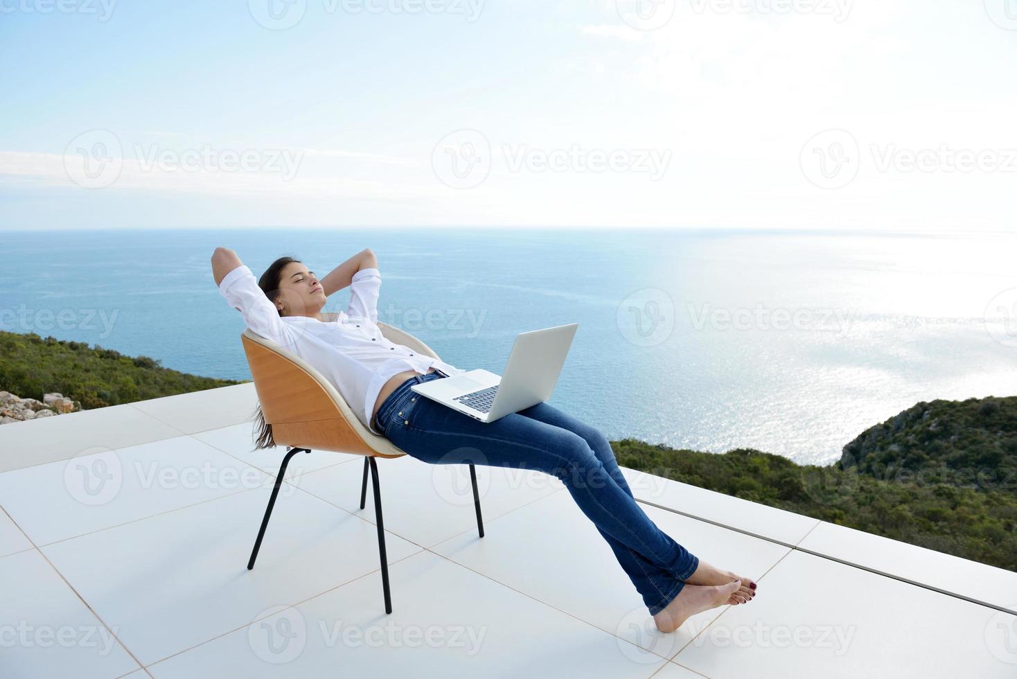 relaxed young woman at home working on laptop photo