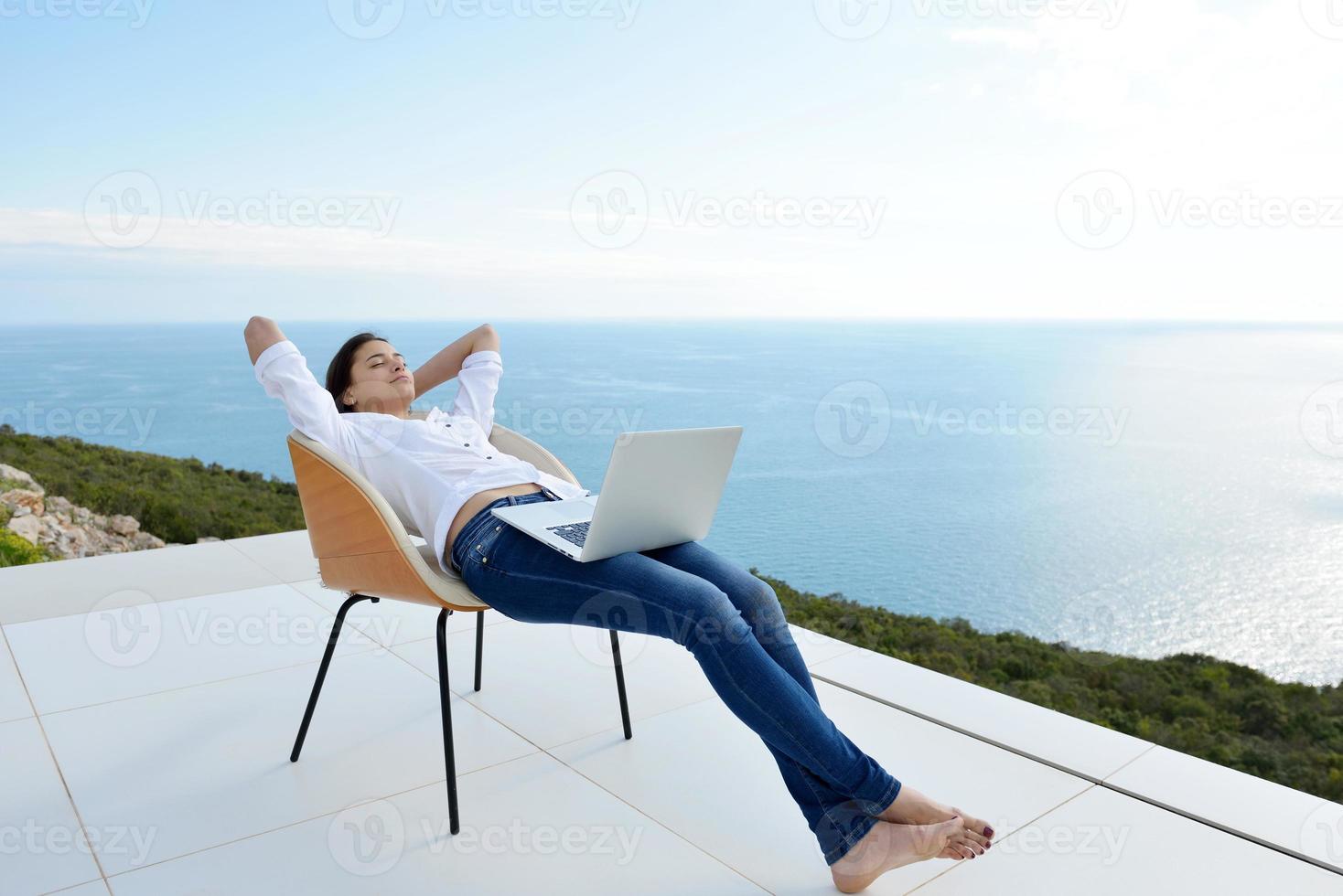 relaxed young woman at home working on laptop photo