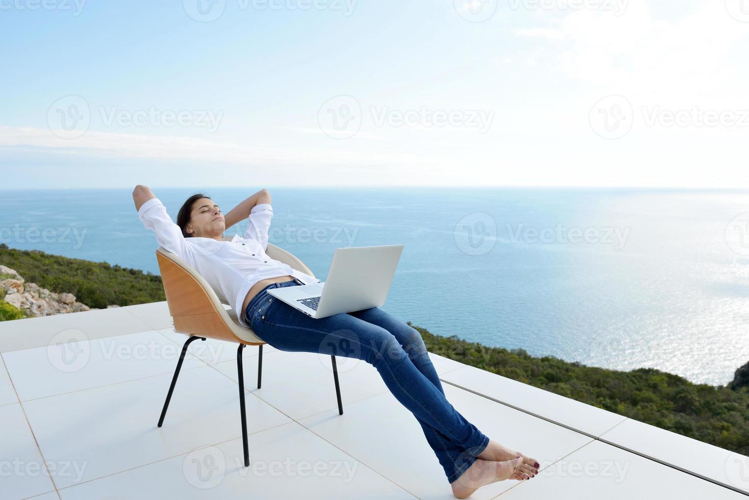 relaxed young woman at home working on laptop photo