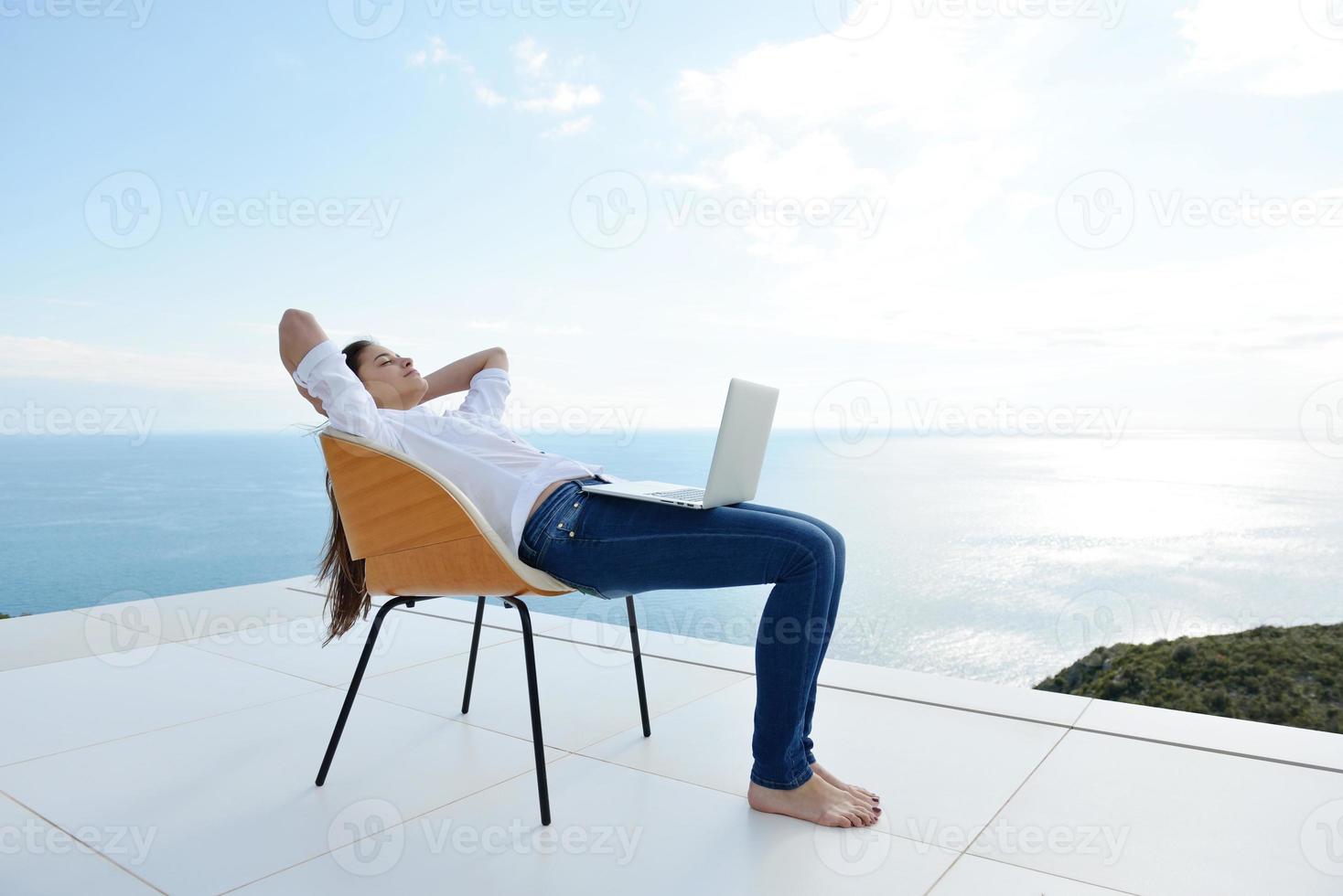 relaxed young woman at home working on laptop photo