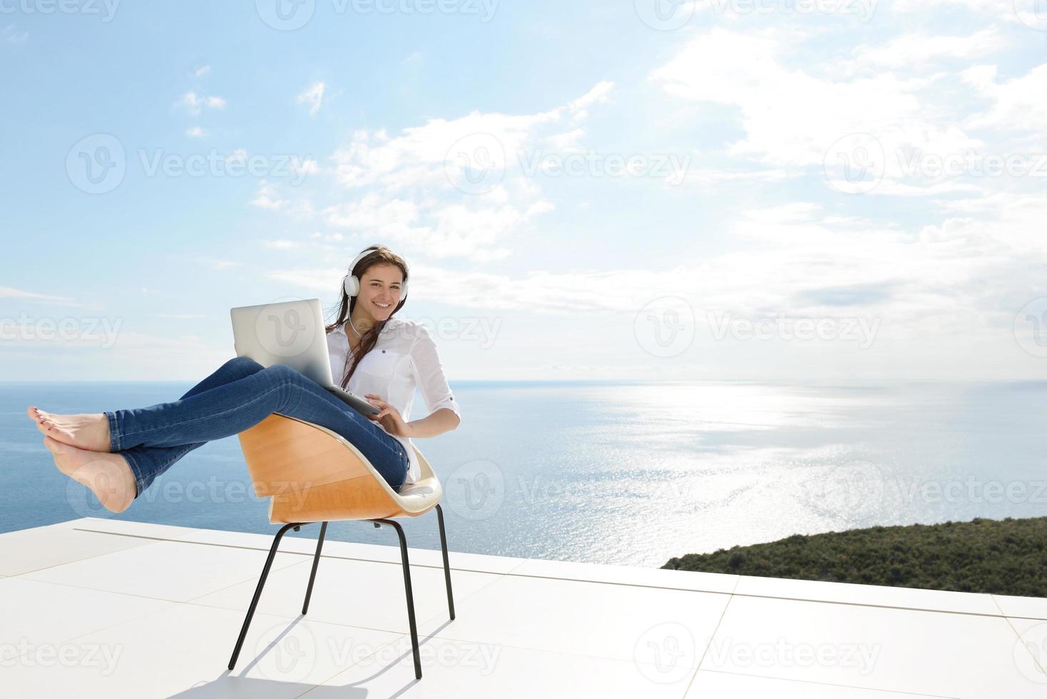 relaxed young woman at home working on laptop photo