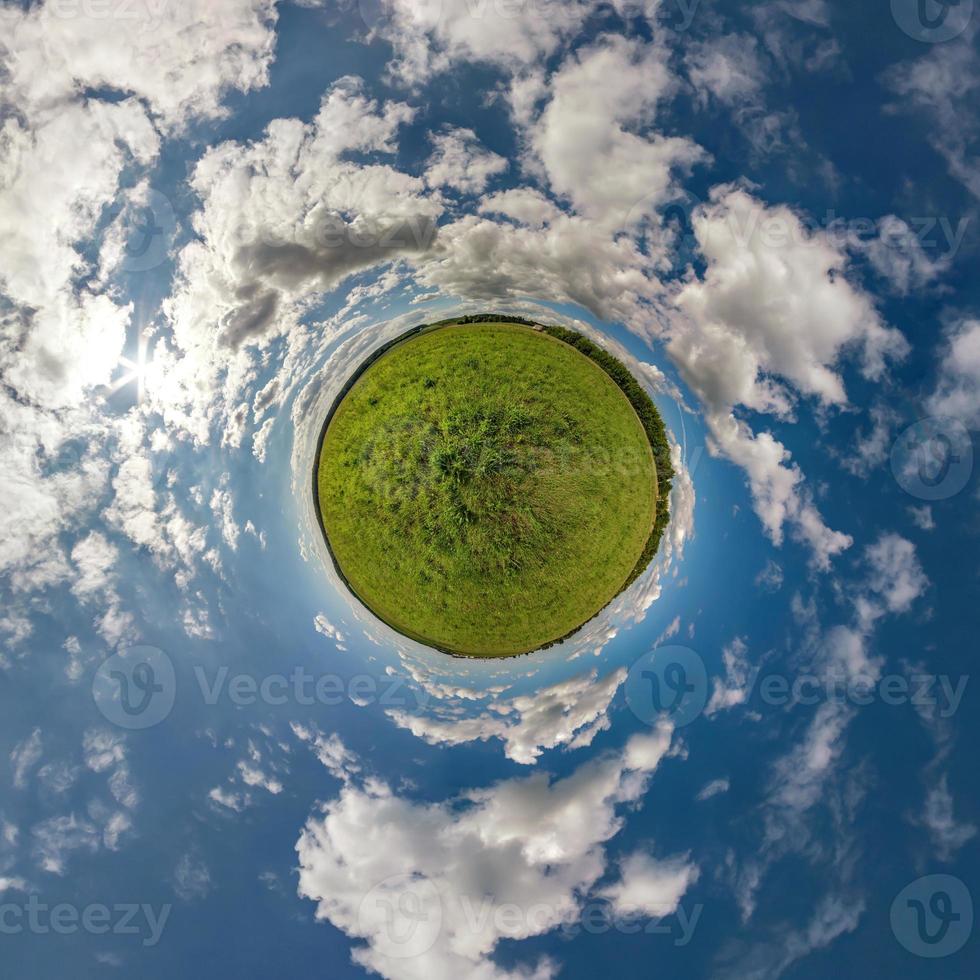 green tiny planet in blue sky with beautiful clouds. Transformation of spherical panorama 360 degrees. Spherical abstract aerial view. Curvature of space. photo