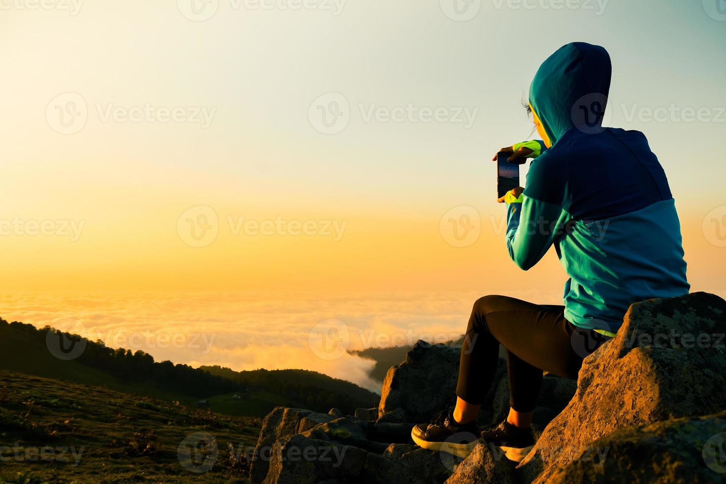 Female persons hands are holding the smartphone and taking a photo of the sunset. Smartphone photography.